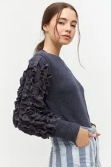 Remera negra de punto con mangas largas abullonadas con volantes.