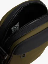 Cartera tipo reporter Tommy Hilfiger color verde militar con detalles en negro. Presenta correa ajustable, bolsillo frontal con cierre y logo metálico de la marca.