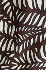 Pantalón de corte holgado con estampado de hojas en tonos marrones y blancos, tiro alto, elástico y cordón ajustable en la cintura, bolsillos laterales.