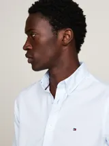 Camisa celeste de corte slim fit con microestampado, cuello abotonado, mangas largas con puños redondeados y logo de Tommy Hilfiger bordado en el pecho.