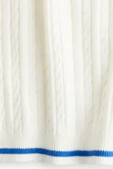 Top corto blanco de punto trenzado con cuello redondo y mangas cortas con ribete azul.