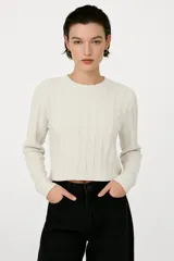 Sweater color crudo de acrílico con ochos, corte holgado y cuello redondo.