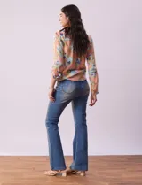 Blusa de gasa estampada a rayas verticales en tonos celeste, lila, naranja y marrón. Tiene cuello a la base con escote en V y botones. Delantera con bolsillo aplicado. Largo de manga regulable con presilla y botón. Terminación anudada opcional.