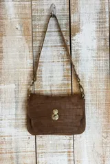 Cartera minibag color marrón con textura tipo piel de cocodrilo. Tiene correa fina para colgar al hombro y cierre con broche metálico dorado.