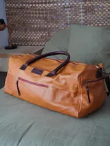 Bolso de viaje tipo weekender de cuero color marrón, con doble asa corta y correa larga desmontable. Cuenta con cierre superior, bolsillos internos y externos con cierre metálico. Forro interior de tela. Marca Sierra Mora.