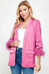 Blazer rosa forrado con mangas 3/4 y detalle de plumas en los puños. Tiene solapas y bolsillos frontales.
