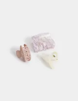 Set de tres broches para el pelo de resina y plástico, con diferentes formas y esmaltados. Incluye un broche ovalado color rosa, un broche con forma de moño color crema y un broche rectangular con estampado carey en tonos lila y blanco.
