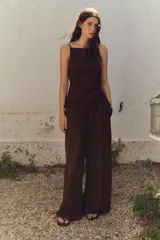 Pantalón marrón de tiro alto con cintura elástica en la espalda, bolsillos laterales, pliegues en la parte delantera y bordados combinados a tono en el ruedo.