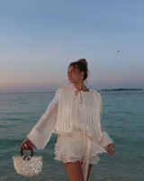 Bolso de mano con forma de media luna cubierto de perlas sintéticas. Tiene asas circulares de madera y detalles de cuentas en la unión con el cuerpo del bolso.