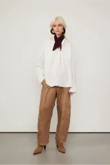 Camisa blanca amplia de algodón, con dos bolsillos en el frente, abotonada y con puños anchos.