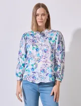 Blusa de satén estampada en tonos lilas y verdes, con cuello a la base y manga larga con puño y botón.