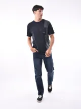 Remera negra de corte oversized con bolsillo en el pecho y detalle de bloque gris en el lateral.