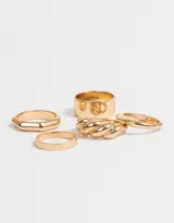Set de cinco anillos dorados con diferentes diseños: uno liso delgado, uno facetado, uno ancho, uno con forma de soga trenzada y uno con forma de gota.