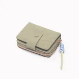 Billetera pequeña color verde con cierre de botón a presión y cierre de cremallera. Incluye un llavero decorativo con cordones de colores.