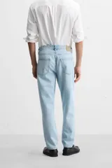 Pantalón de jean celeste de corte slim fit y tapered, con cinco bolsillos, efecto lavado y cierre frontal con cremallera y botón.