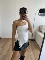 Top blanco de lycra, con un solo hombro y corte irregular en la parte inferior.