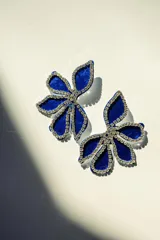 Par de aros con forma de flor azul de terciopelo, contorneada con strass y cierre a presión de acero inoxidable.