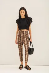 Pantalón babucha con estampado de piel de serpiente, ajuste en los tobillos, elástico en la cintura y cordón para ajustar. Cuenta con terminaciones metálicas, bolsillos diagonales en el frente y falsos bolsillos ojal en la espalda.