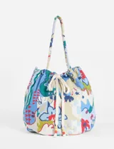 Bolso tote de tela estampada con motivos florales y geométricos en tonos azul, verde, rojo y blanco. Tiene doble asa de hombro y cierre con cordón ajustable con cuentas de madera.