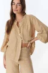 Camisa color beige de lino, con cuello mao, mangas largas abullonadas y cierre frontal con botones.