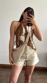 Riñonera de cuero color crudo con correa ajustable y hebilla metálica.