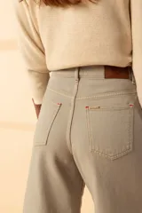 Pantalón de jean color gris claro, de corte recto y tiro alto, con tajos laterales y terminación desflecada.