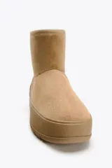 Botín color beige de caña baja, con interior de efecto pelo y suela tipo flatforma.