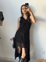 Vestido corto de encaje negro con escote en V, sin mangas y corte irregular.