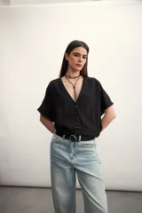 Blusa rosa de lino con escote cruzado en V y mangas cortas. Incluye un collar con cordón negro y dije dorado.