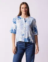 Blusa celeste con estampado floral en tonos azules y blancos, de corte recto, cuello redondo y mangas cortas.