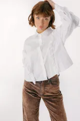 Camisa celeste con cuello clásico, cierre frontal con botones y mangas largas con volados.