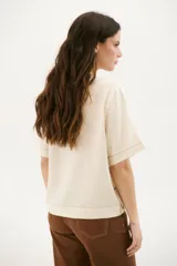Blusa color crudo de lino con cuello redondo y mangas cortas.