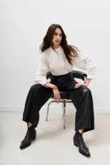 Pantalón negro de cuerina, corte jeanero, tiro alto y pata ancha.