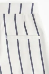 Pantalón ancho de tiro alto color blanco con rayas verticales azules, bolsillos laterales y cierre frontal oculto.