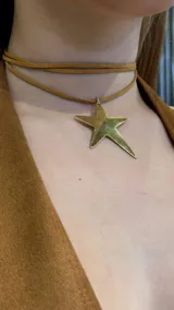 Gargantilla doble de gamuza color marrón claro, con dije de estrella dorada.