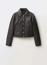 Chaqueta corta de cuero negro con cuello camisero, cierre frontal con botones a presión plateados, bolsillos laterales y puños abotonados.