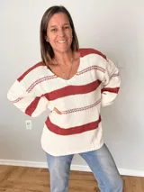 Sweater tejido a rayas horizontales color ladrillo y blanco, con cuello redondo y mangas largas.