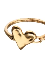 Pulsera semirrígida de aleación de metales bañada en oro 18k, con un dije central en forma de corazón irregular y un cierre tipo gancho. El brazo de la pulsera presenta una sección con espiralado decorativo.
