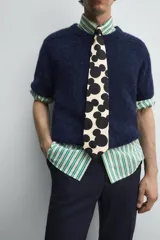 Cárdigan azul marino de manga corta tejido en hilatura con lana y alpaca, de textura suave. Tiene cuello redondo, rib en los bordes y cierre frontal con botones. Edición especial Harry Lambert for Zara x Disney.