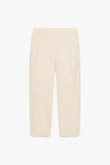 Pantalón bombacho color beige de lino, con cintura elástica, bolsillos frontales y bolsillos de parche en la espalda.
