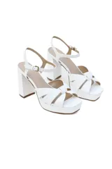 Sandalias de cuero blanco con plataforma y taco alto forrado. Presentan tiras anchas cruzadas en el empeine y pulsera con hebilla al tobillo.