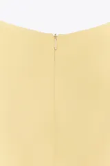 Mono corto color amarillo pastel, de cuello redondo y sin mangas. Presenta una abertura en la parte delantera de la falda y cierre trasero con cremallera.