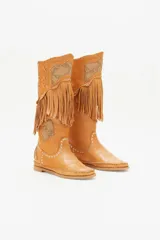 Bota alta color cuero con flecos, apliques de cuero con estampado reptil, tachas plateadas y costuras a la vista.