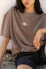 Remera negra de corte oversize con estampa trasera con un sol y texto en color naranja.