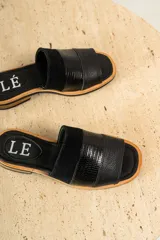 Sandalias de cuero negras con diseño de tiras cruzadas y detalle de elástico en el talón.