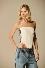 Corset blanco con líneas verticales negras en los laterales, corte asimétrico y estructura ajustada.