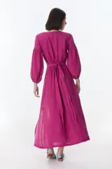 Vestido color beige de lino, con escote en V, mangas largas abullonadas y lazos frontales. Tiene corte a la cintura y falda larga con tajo frontal.