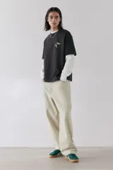 Remera negra de corte holgado y mangas cortas, con cuello redondo y estampado pequeño de llave de hotel en el pecho.