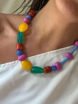 Collar corto con cuentas de cristal checo y acrílico de colores: rojo, azul, amarillo, verde y fucsia. Se cierra con cadena de acero quirúrgico y ganchito para regular el largo.