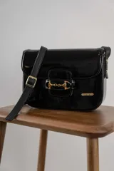 Bolso de cuero color tostado, con cierre frontal y correa ajustable.